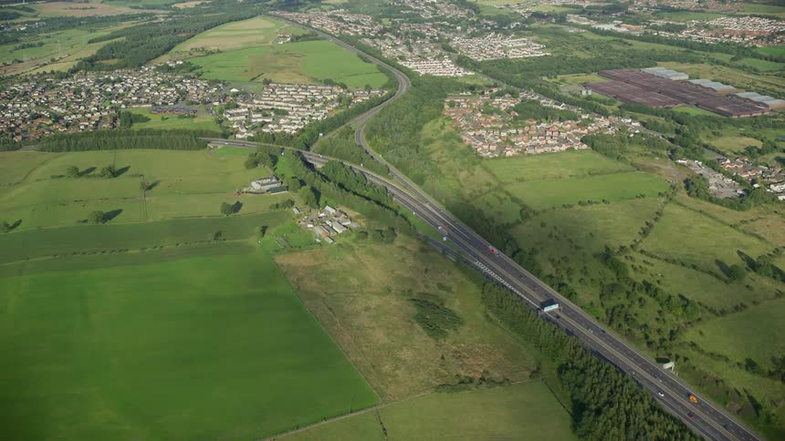 A rural town with many houses next to a highway and large patches of grass