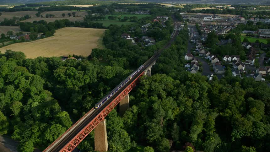 Aerial view of a bridge with a train passing through the middle of an urban city