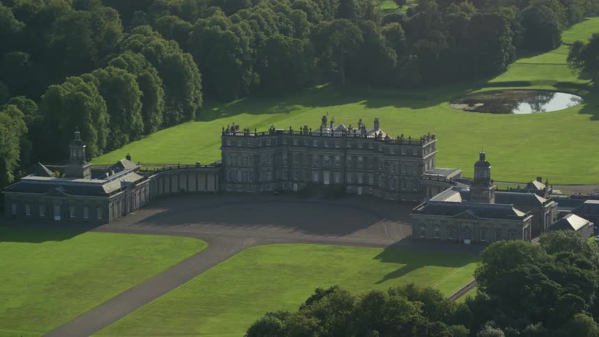 Aerial view of a manor house next to grass field and trees during day time
