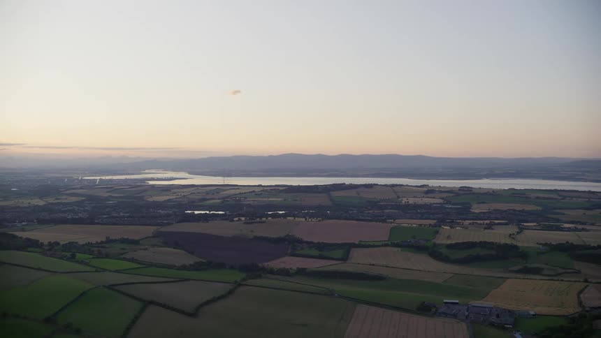 A wide open aerial view of farmland with grass and crops