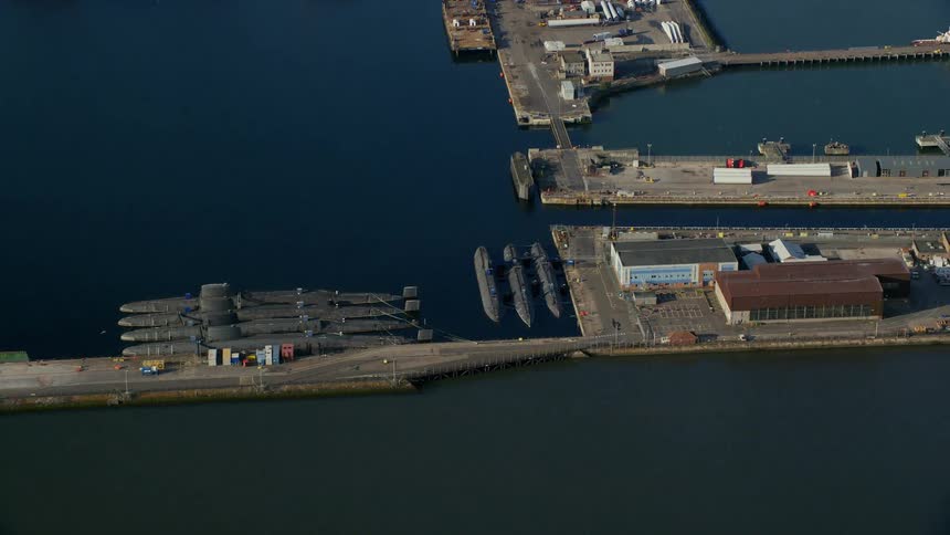 Aerial of a marina with ships docked and buildings near the shores on a bright sunny day
