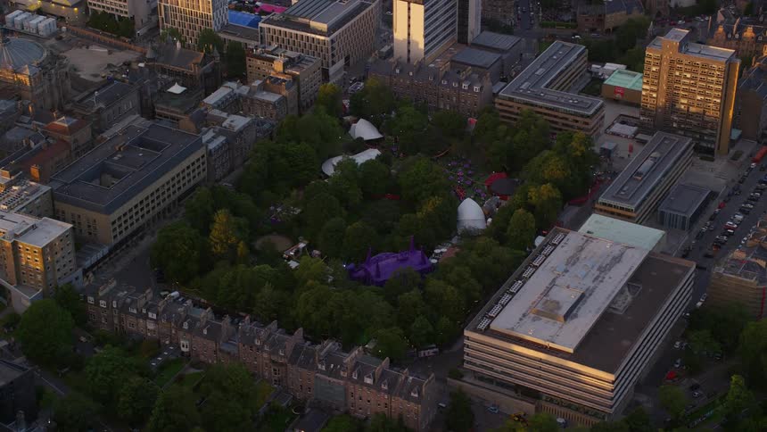 An event in a park with lots of trees that is surrounded by buildings