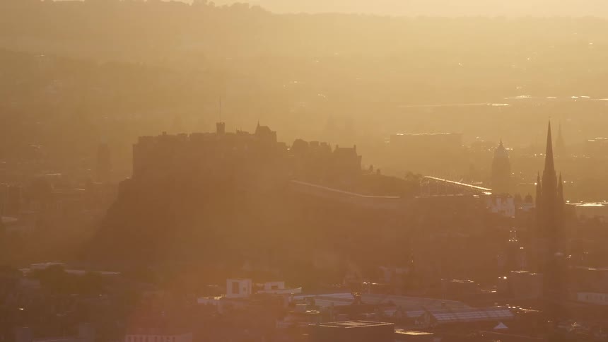 Heavy fog obscures a historical city below a hill