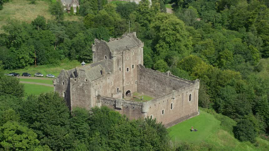 Aerial view of a castle surrounded by nature with people visiting