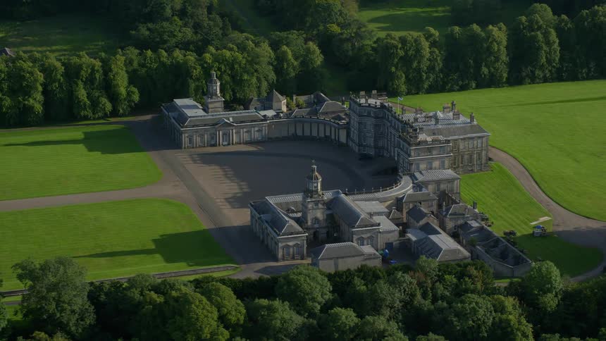 Aerial of a large castle on a green field of grass