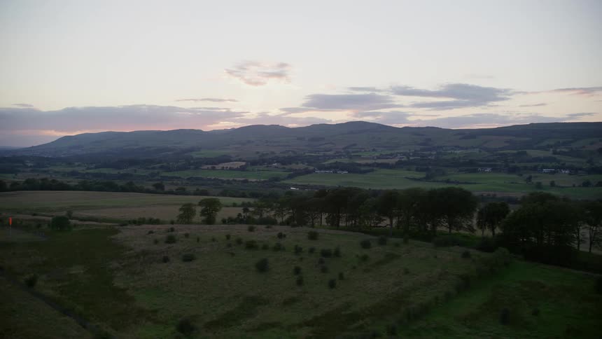 Aerial view of a mountain range and pasture at dawn