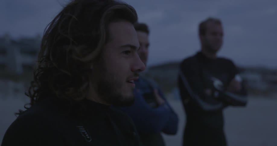 Men are on a beach at sunset