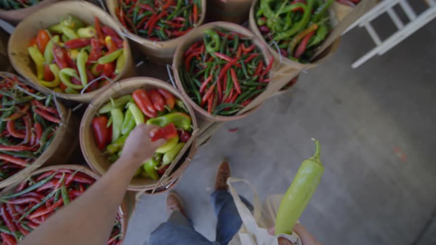 Customer selects peppers from produce displayed at market