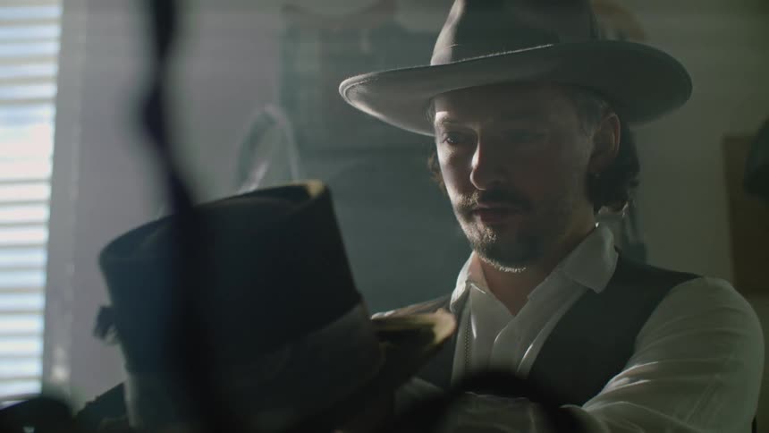 Man wearing western style hat examines tall hat