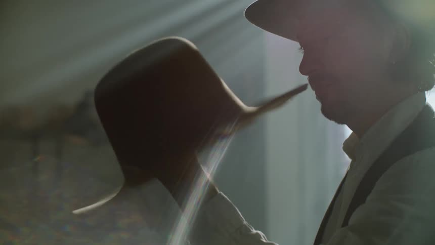 A man twirling a beige hat in his hands