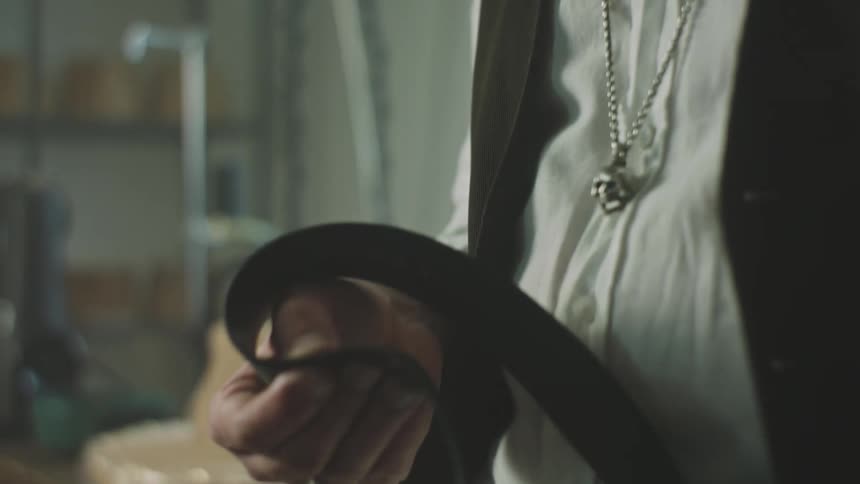 Man sewing a tie with a needle
