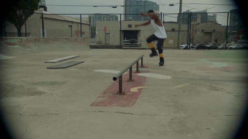 A man is roller skating on the iron bar of the skate park