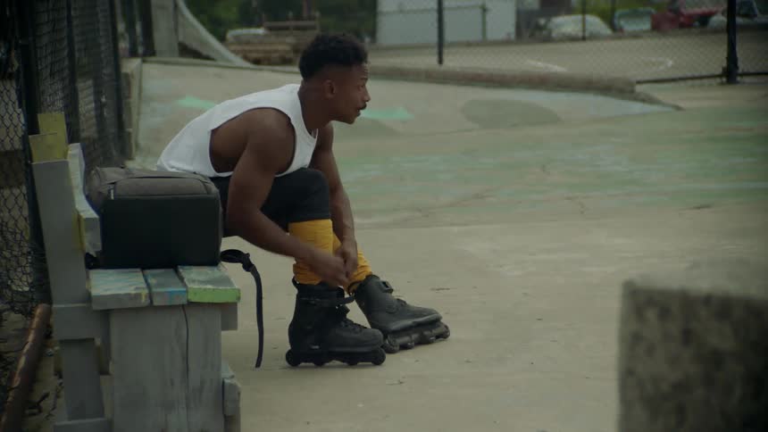 Man sitting on a bench tying the laces of rollerblades