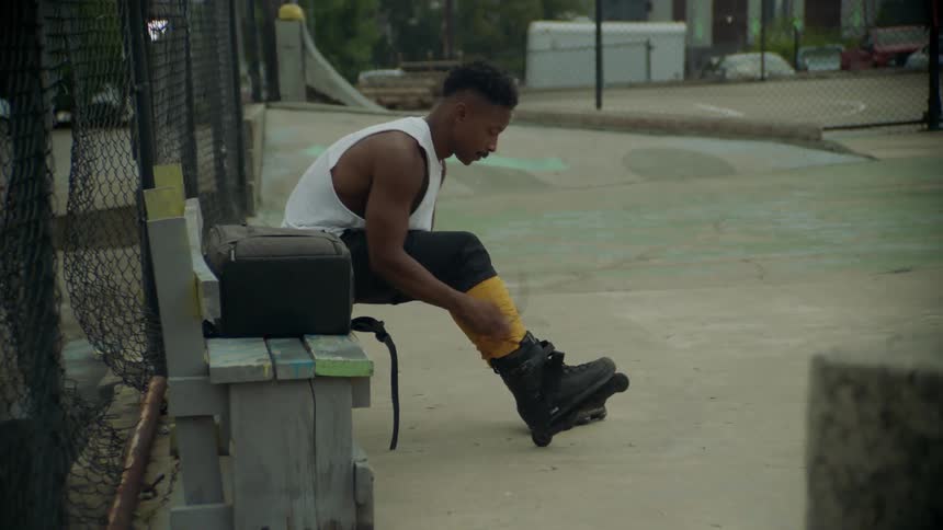 Man sitting on a bench puts on roller skates
