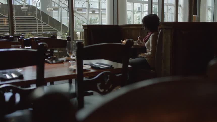 Woman stirring her warm drink while sitting at a cafe table
