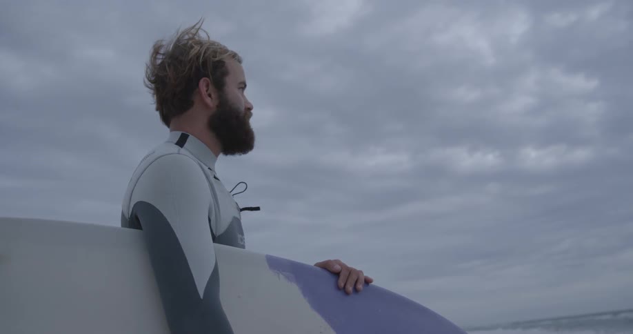 Man holds a surfboard on a cloudy day