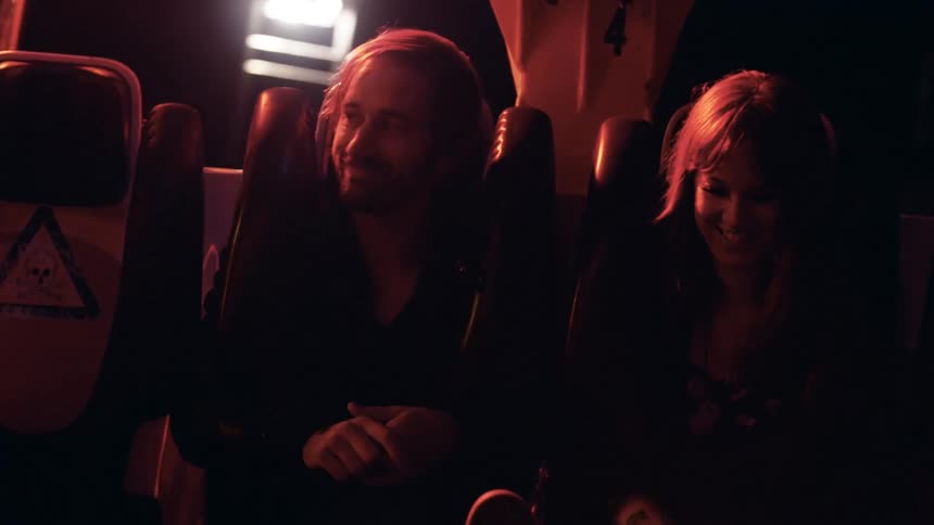 Man and woman ride a fair ride together at night