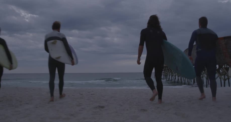 Surfers head towards the ocean with their boards