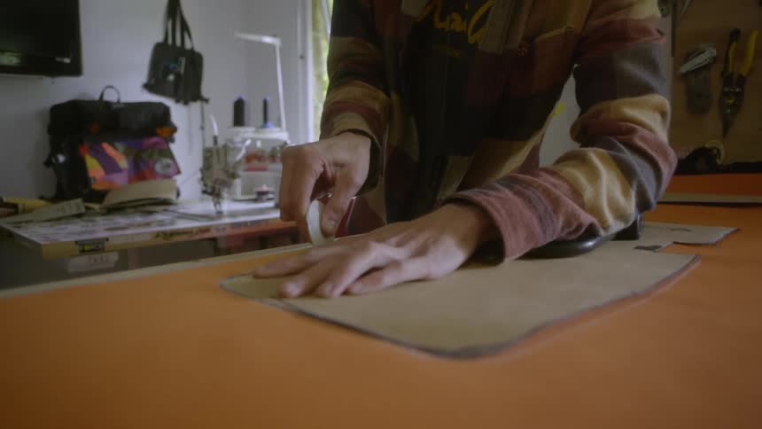 A person drawing an outline around a brown material on a counter top in their design room