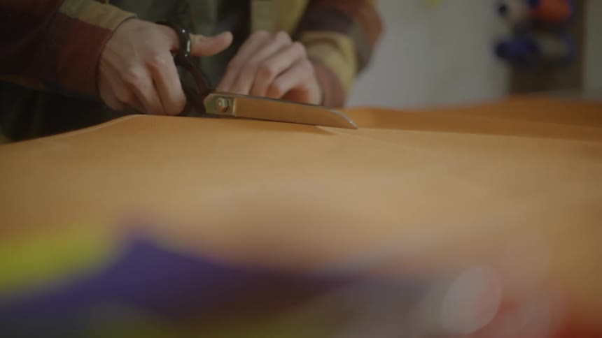 A persons hand cutting fabric with scissors