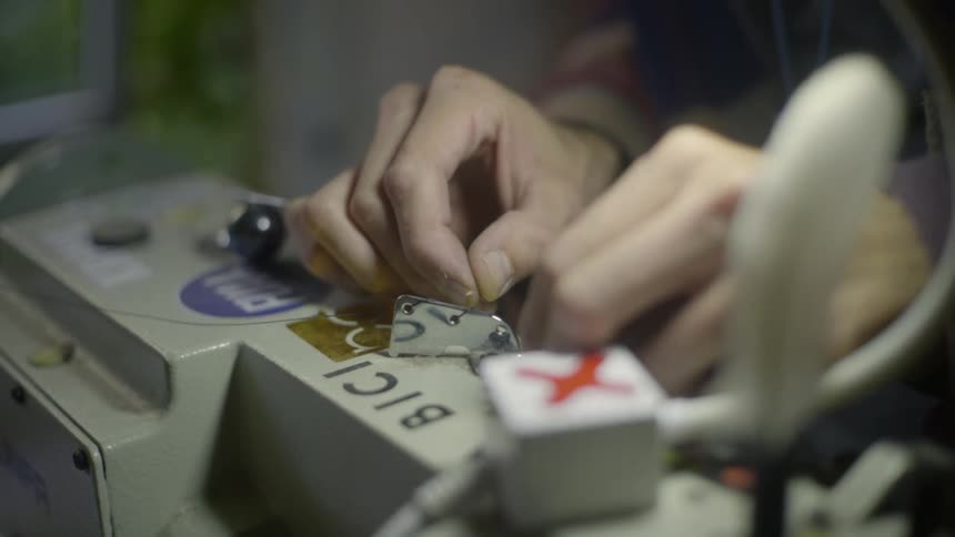 A persons hand threading a needle on a sewing machine
