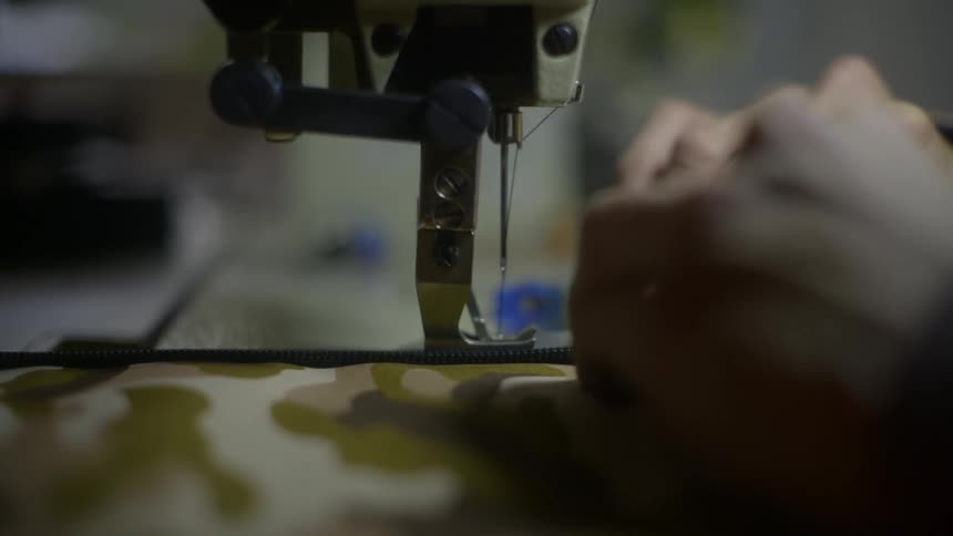 Human hand handling fabric on a sewing machine