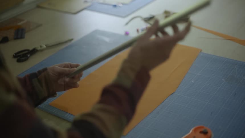 A craftsman is measuring fabric
