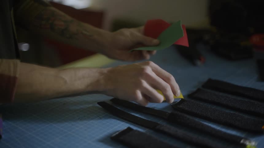 A person sorts through small pieces of square fabric atop a table