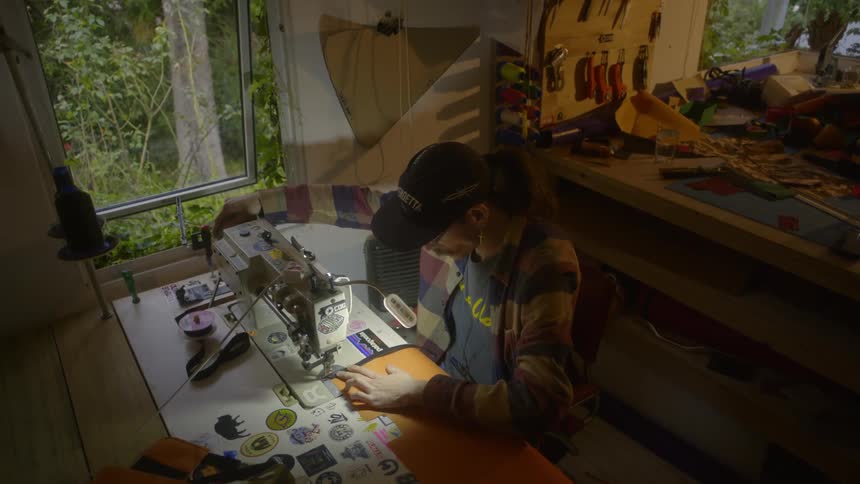 Man sitting at a table and using a manufacturing machine to sew a piece