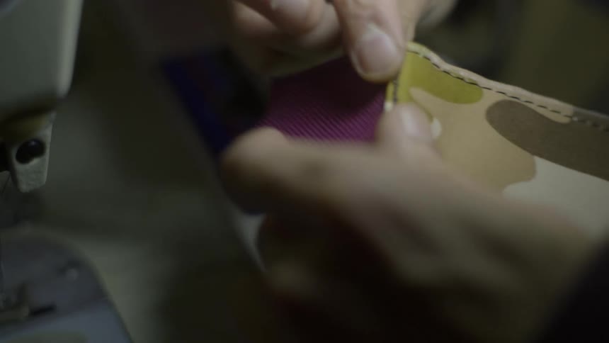 Hand of a person using a lighter to melt a thread on leather