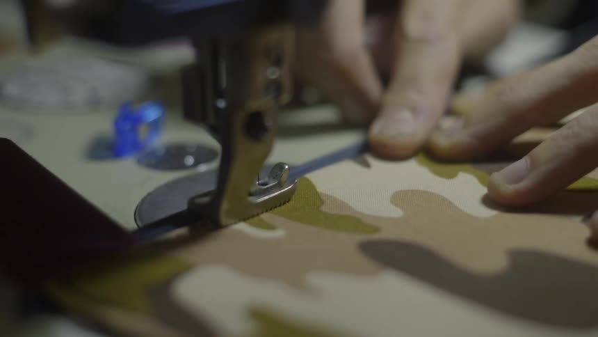 Close up of tailors hands using sewing machine