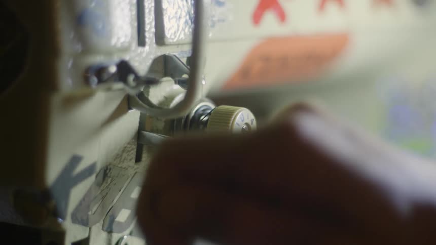 A person threads a sewing machine