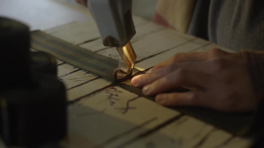 Carpenter uses a tool to cut car seat belts create straps