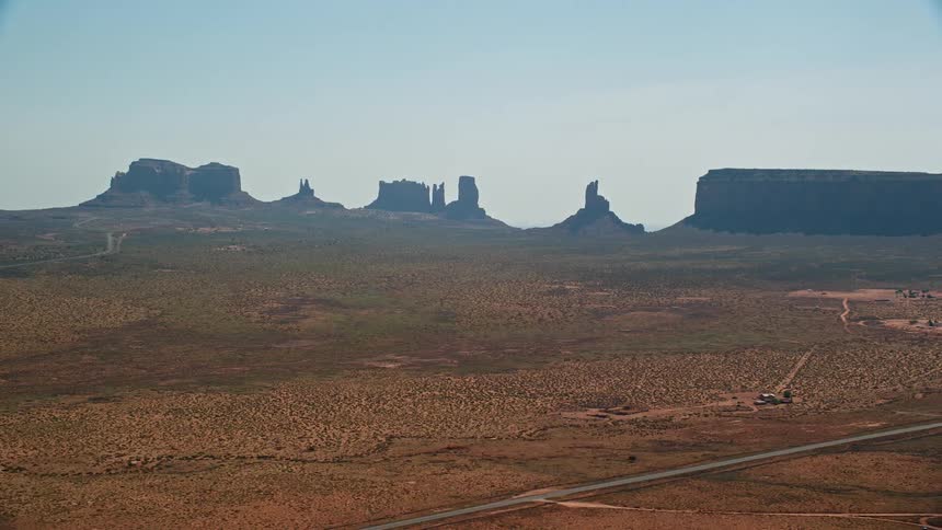 Aerial view of rocky mountains with geological formations in the background and pasture with roads