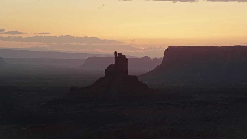 Drone view of rock formations in the desert as the sun shines on the horizon