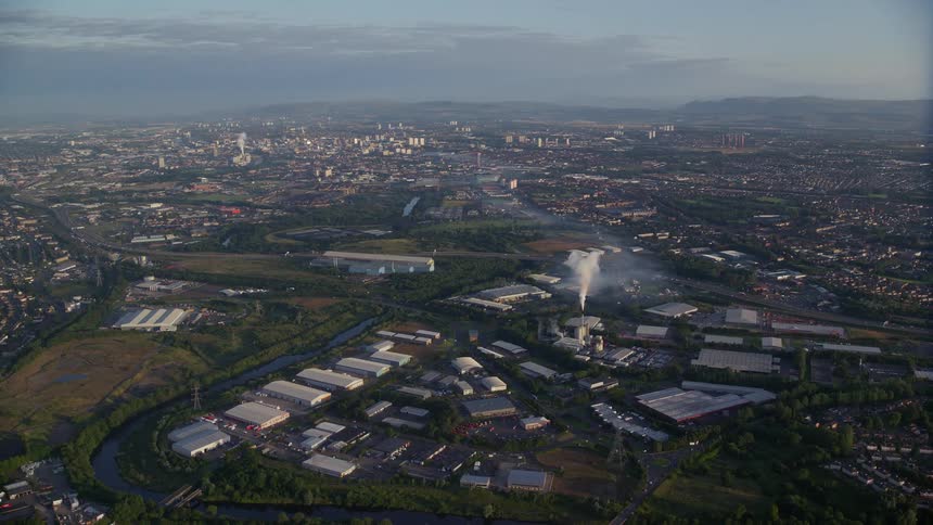 Smoke emerges from chimney of manufacturing plant situated near river