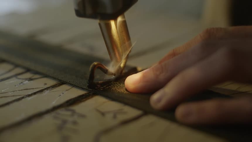 Close up of the hand of a carpenter etching a piece of wood and cutting a seat belt