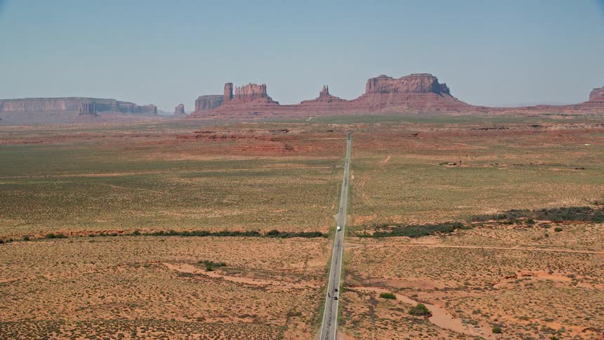 A desert with a huge road in the middle and in the background there are mountains