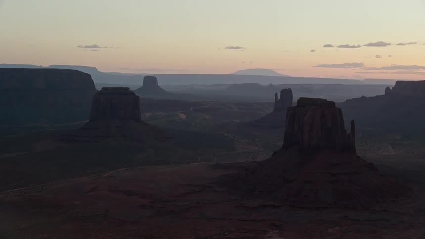 Fog covers mesa terrain under a red tinted sky at sunrise