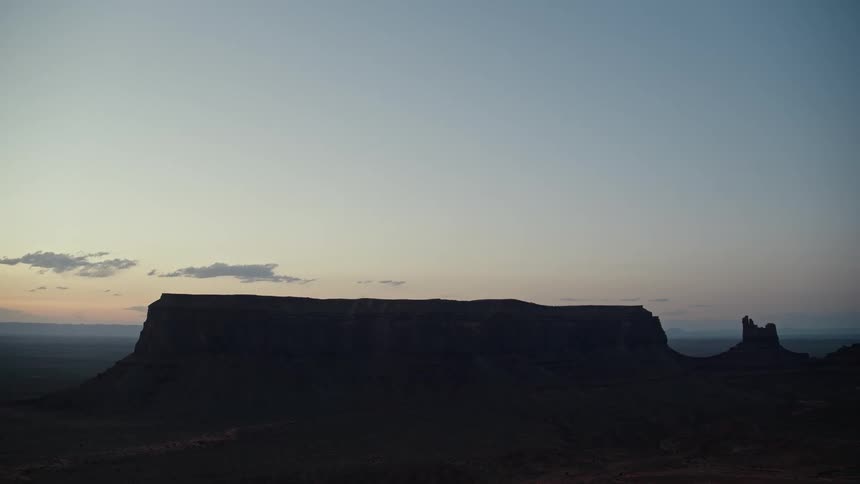 Rock formations stand silhouetted against a red tinted hazy horizon