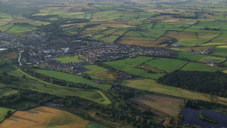 A town with many buildings in it is surrounded by numerous grassy fields