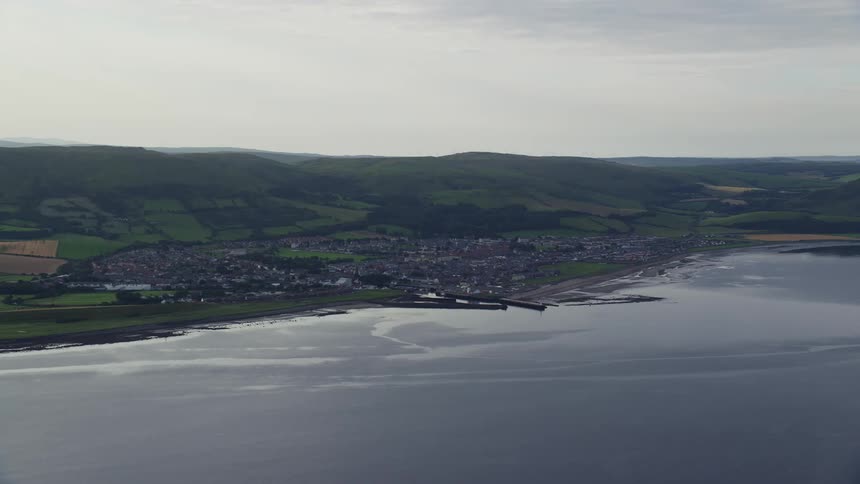 Aerial view of a small seaside town with a mountain range in the background