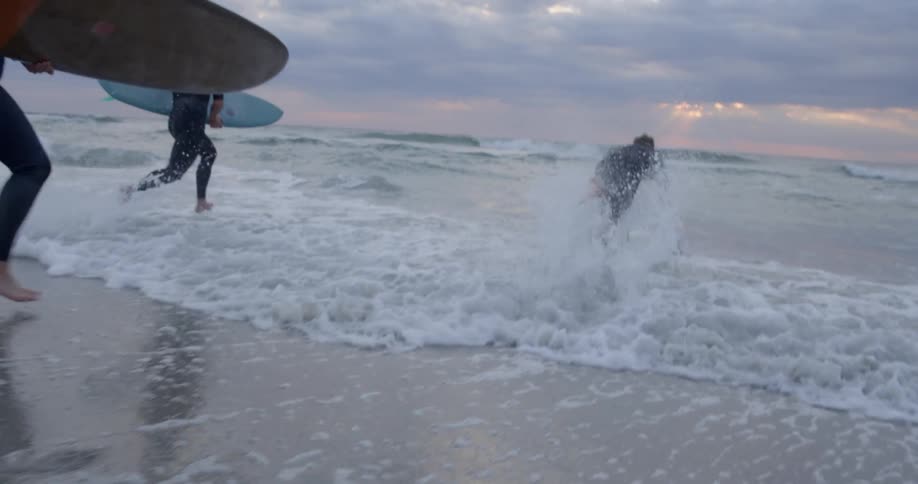 People run towards the ocean with surf boards