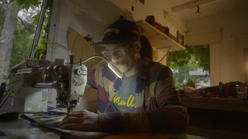 Man sitting and sewing a cloth with a sewing machine