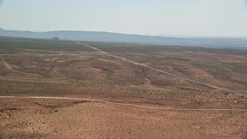 Aerial view of road through desert mountains on horizon