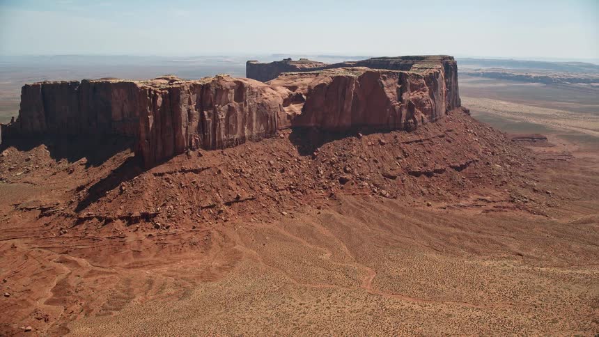 Plateau topped formation stands surrounded by scrub land a distance from foggy horizon