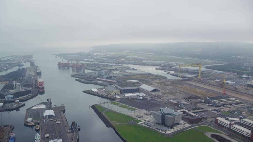 Drone view of a river through a marina with boats docked near a city area in the early morning as fog settles over the water