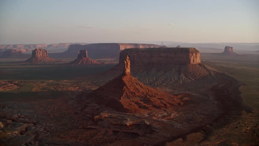 A pointy rock formation in a desert with some other mesa formations
