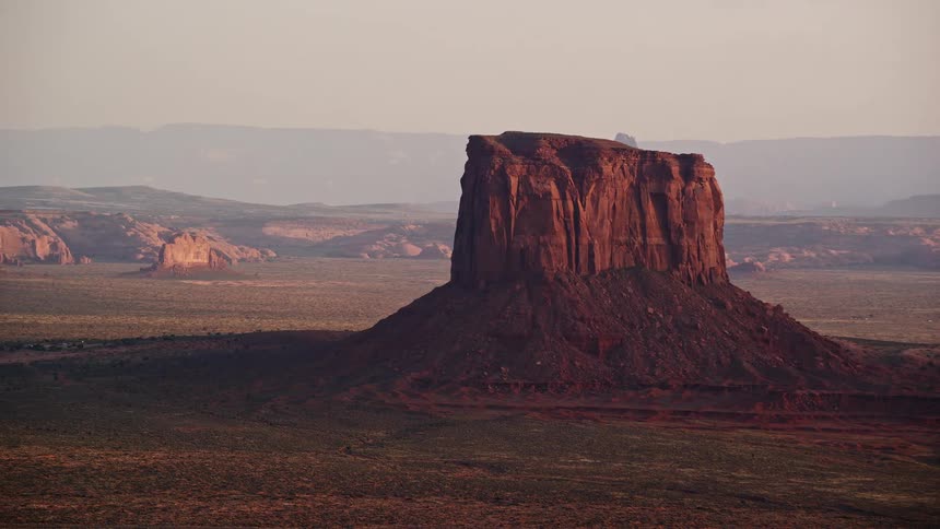 Drone view of rock formations in the desert as the sun shines and hazes across the sky