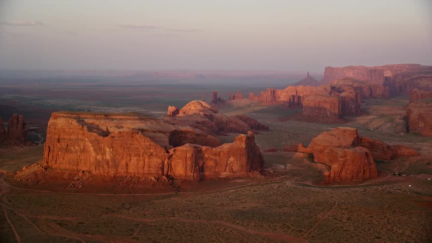 A high rock formation in the desert with a small dirt road
